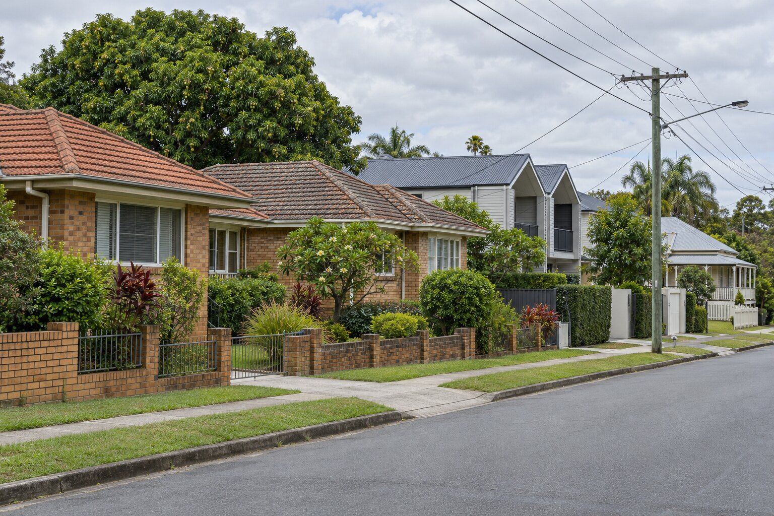 Roofing, Nundah: post-war brick and tile homes beside newer townhouses with Colorbond roofs on a suburban street